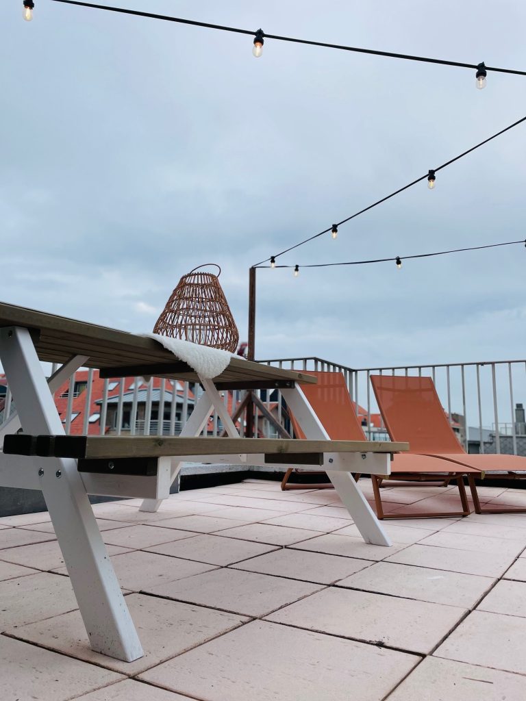 Het terras van Sea5 met ligstoelen en sfeerverlichting